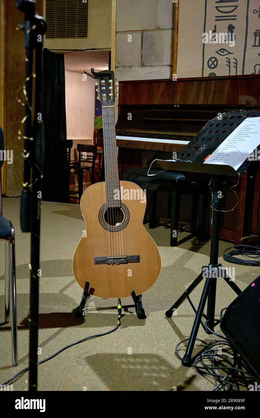 Un'immagine di una chitarra acustica si trova sul palco vicino a uno stand musicale Foto Stock