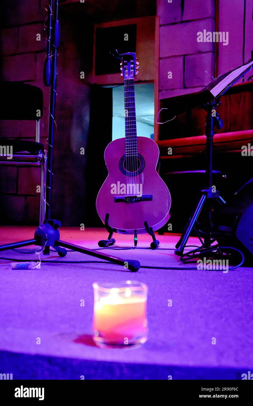 Un'immagine di una chitarra acustica si trova sul palco vicino a uno stand musicale Foto Stock