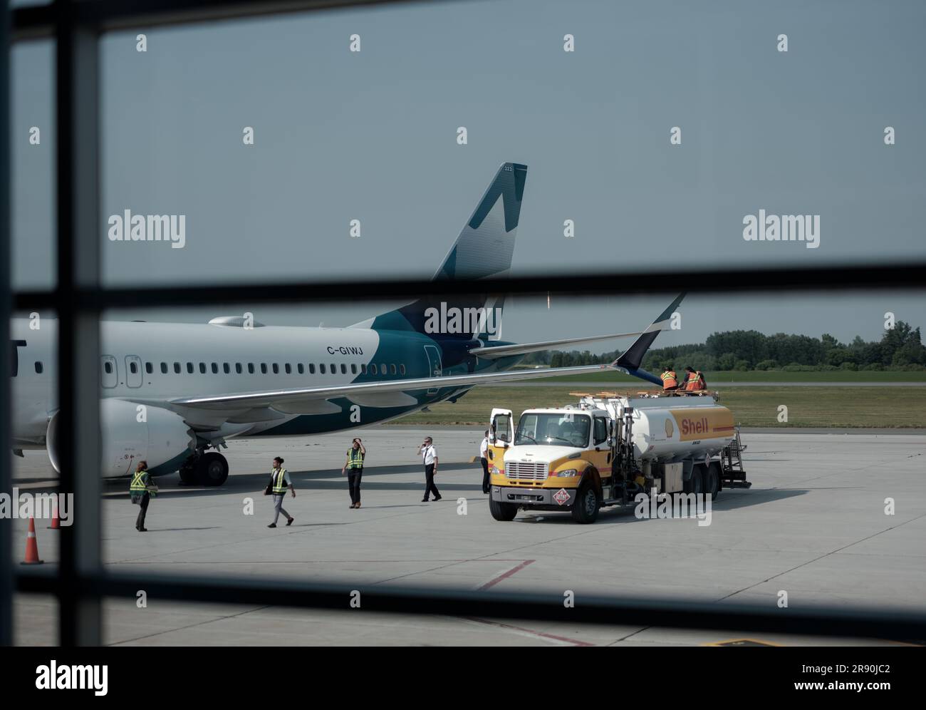 I dipendenti dell'equipaggio di terra e di volo ispezionano i danni ad un'ala Boeing 737-800 dopo aver colpito accidentalmente un camion parcheggiato per il rifornimento. Foto Stock