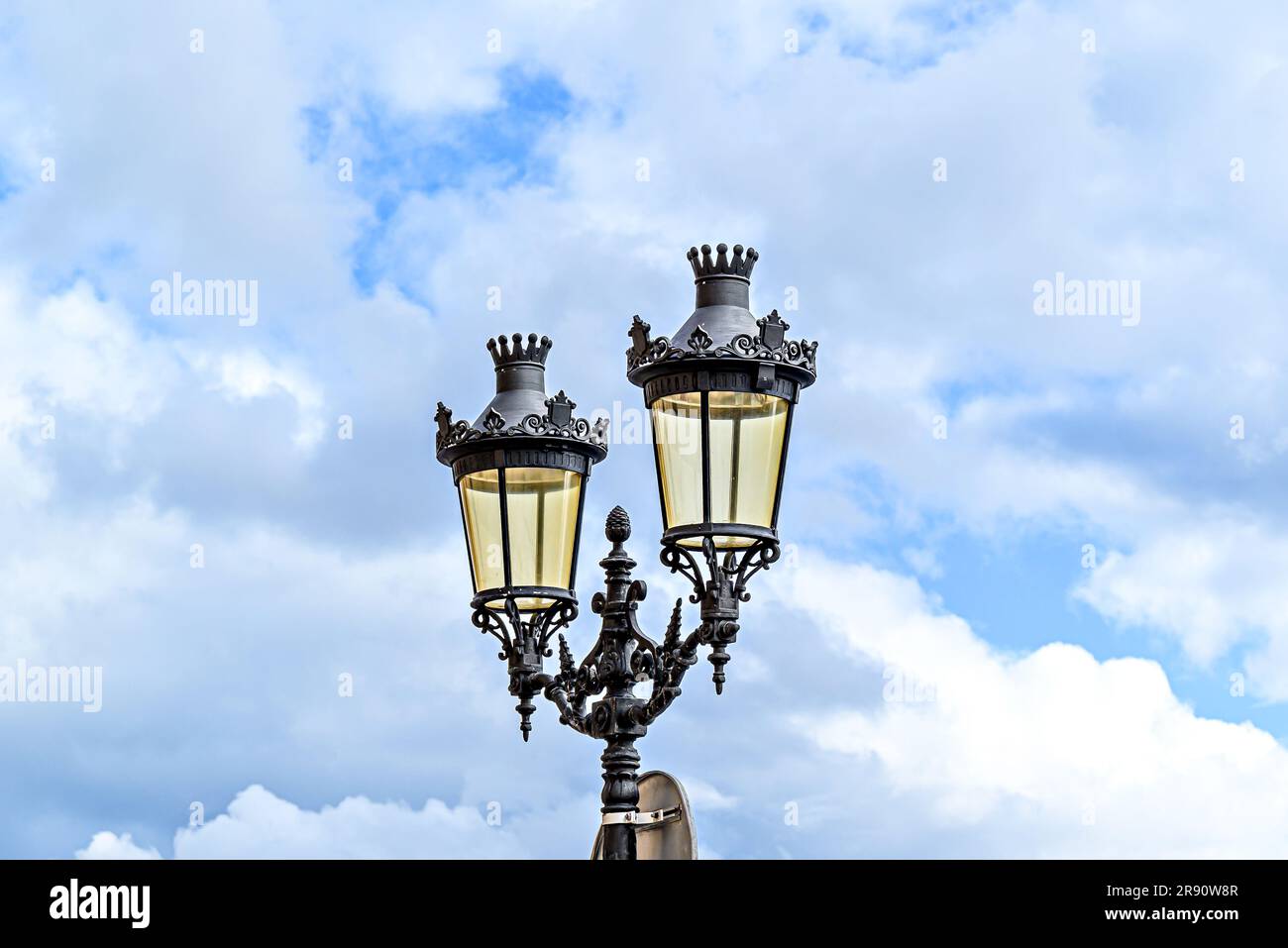 Lampione in ferro battuto sotto un cielo blu con nuvole bianche nella Plaza des Born a Ciutadella, Minorca Foto Stock