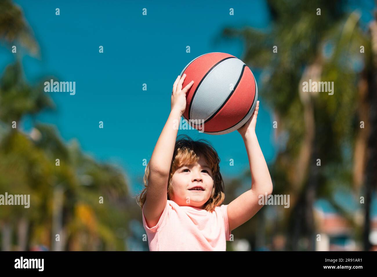 Bambino che gioca a basket con pallone da basket. Bambino con palla da  basket sullo sfondo del cielo, allegro e piacevole Foto stock - Alamy