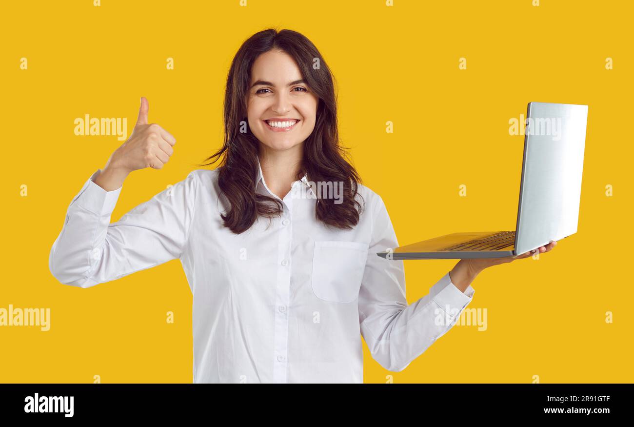 Donna felice soddisfatta che lavora in remoto utilizzando un notebook mostrando il gesto del pollice in alto. Foto Stock