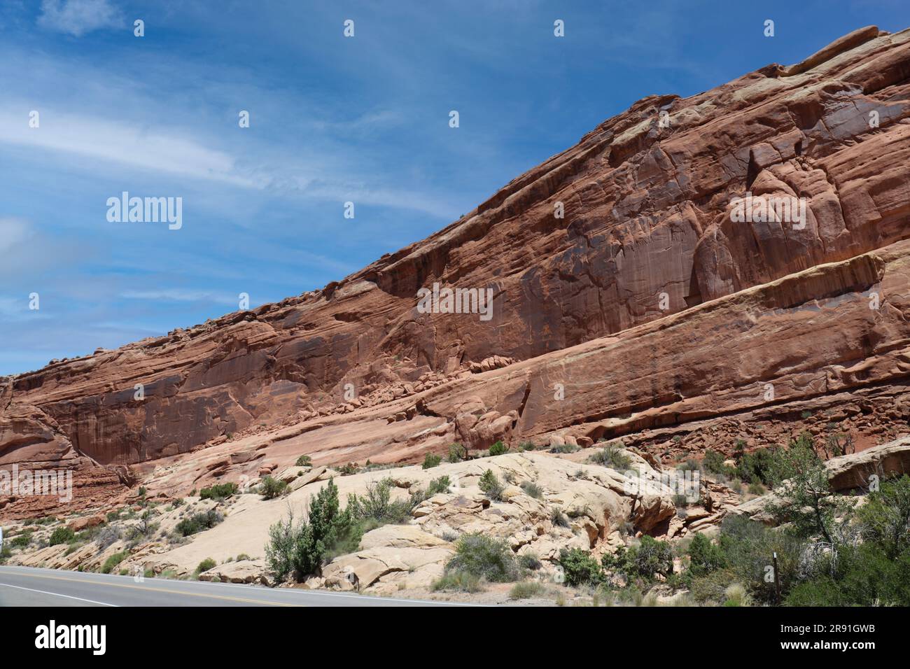 Strati di Entrada e arenaria Navajo costeggiano la strada nel Parco Nazionale degli Arches a Moab, Utah, USA, con cieli azzurri, in estate Foto Stock