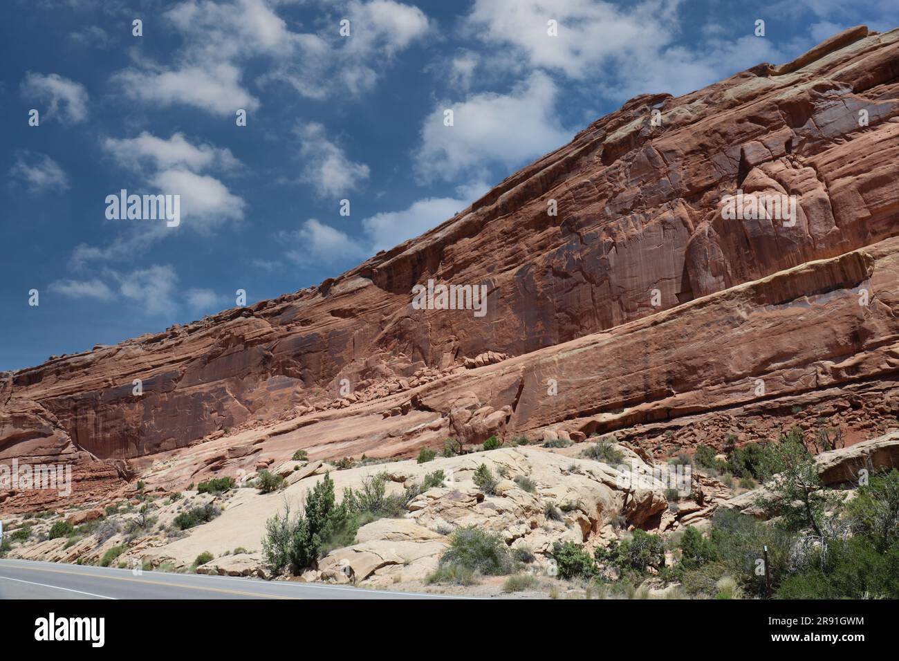 Strati di Entrada e arenaria Navajo costeggiano la strada nel Parco Nazionale degli Arches a Moab, Utah, USA, con cieli azzurri, in estate Foto Stock