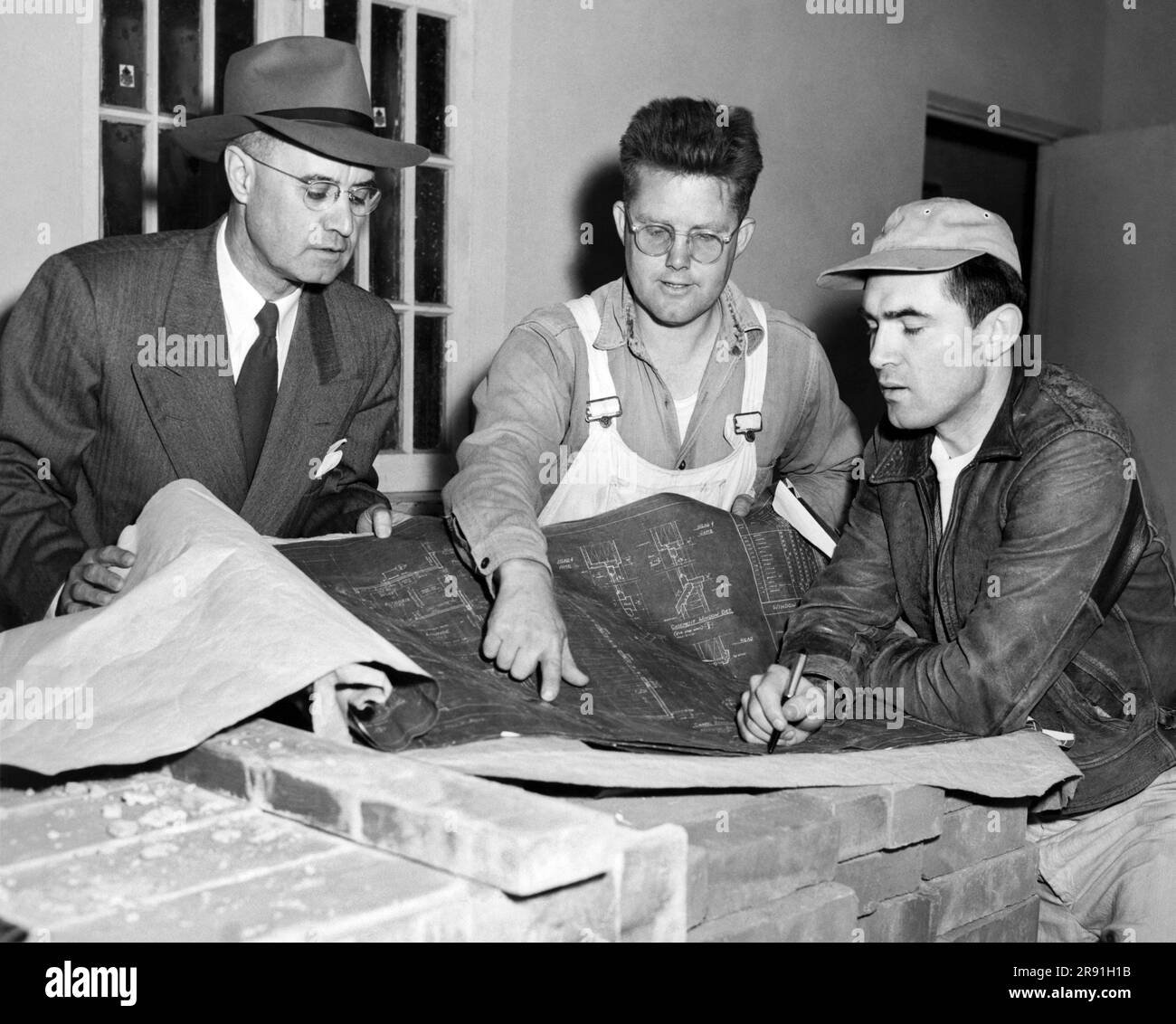 San Francisco, California: c. 1951. Tre uomini si riuniscono su una serie di progetti per un edificio. Foto Stock
