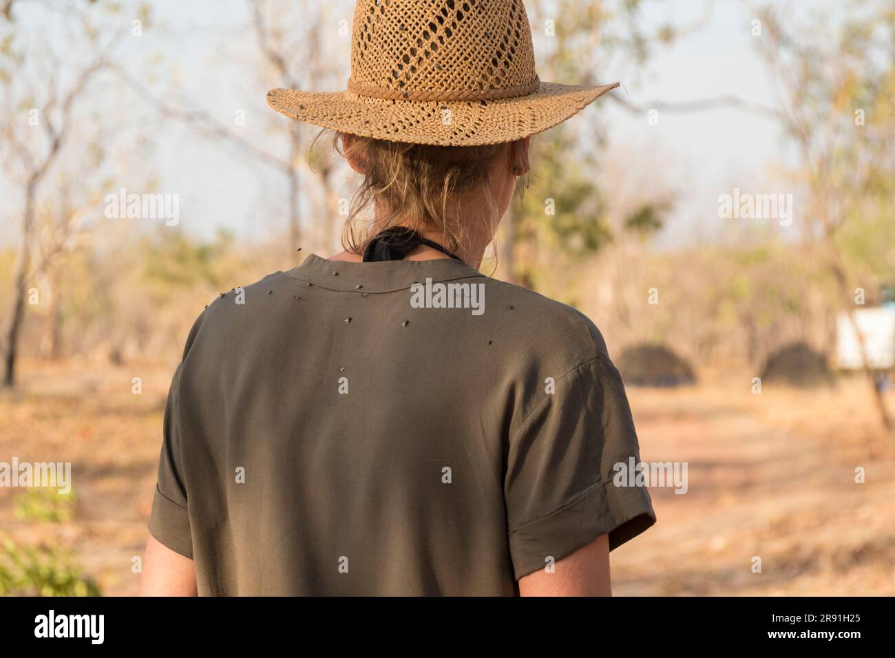 Una donna con un cappello da sole è coperta di mosche sulla schiena nel caldo dell'entroterra australiano Foto Stock
