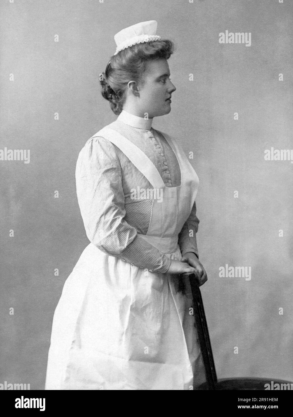 Stati Uniti: 1906 Un ritratto di una giovane infermiera in posa in uno studio. Foto Stock