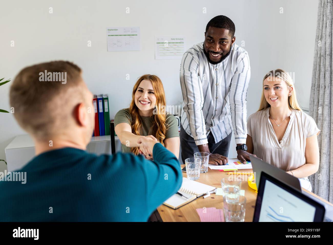 Donna d'affari sorridente e uomo d'affari che fanno la stretta di mano sul posto di lavoro Foto Stock