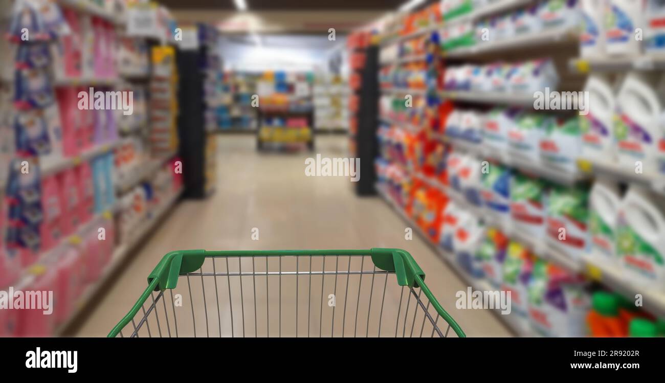 Un carrello della spesa è collocato al centro di una corsia di un supermercato piena di una serie di articoli di alimentari Foto Stock