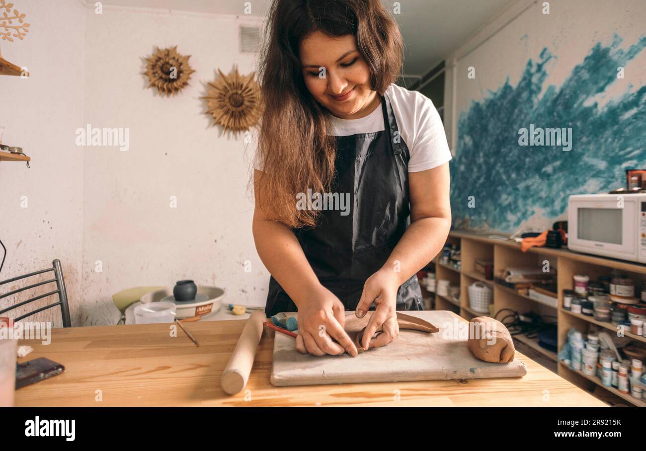 Sorridente vasaio che modella l'argilla in officina Foto Stock