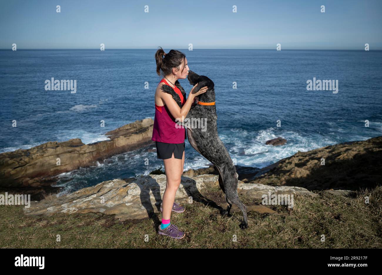Donna che bacia cane vicino al mare Foto Stock