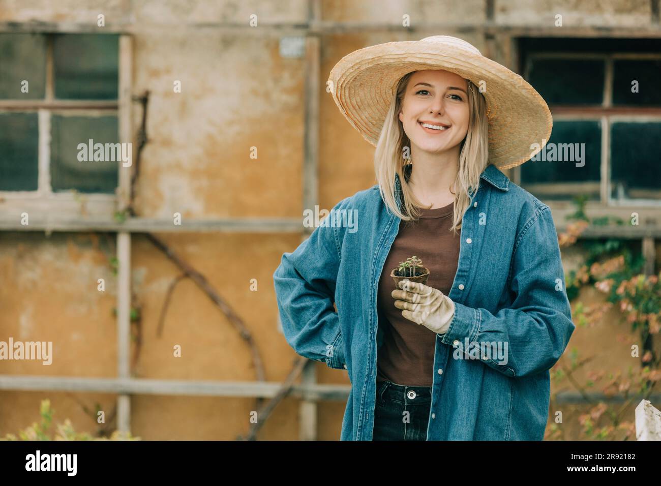 Donna sorridente che tiene piantine di verdure in giardino Foto Stock