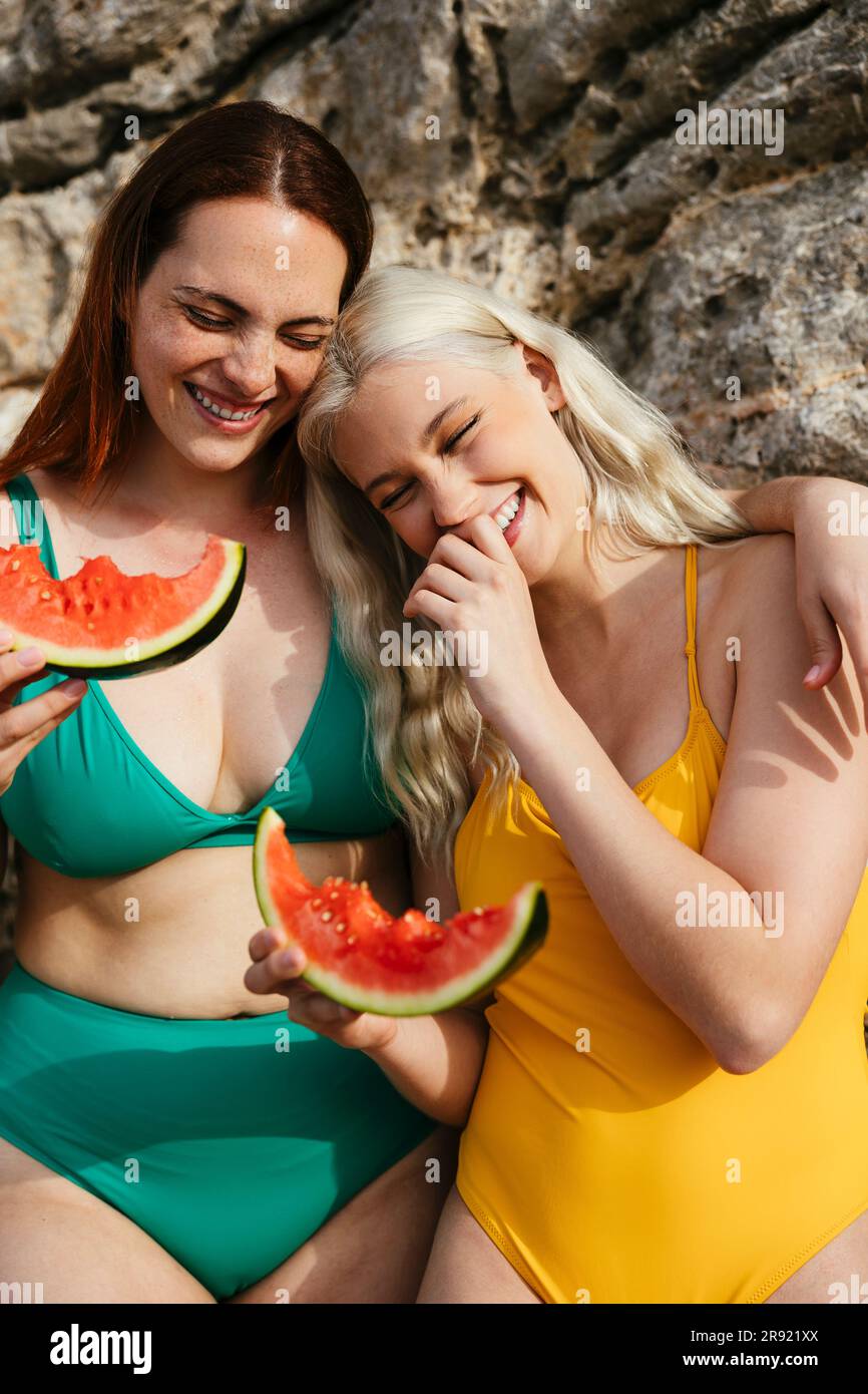 Amici felici che si godono l'anguria in spiaggia Foto Stock