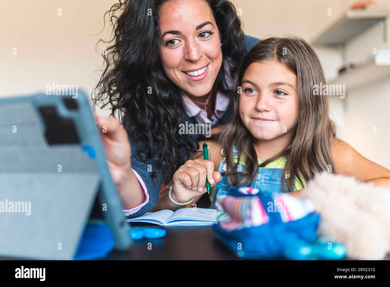 Madre che fa scuola a casa sua figlia con un tablet PC a casa Foto Stock