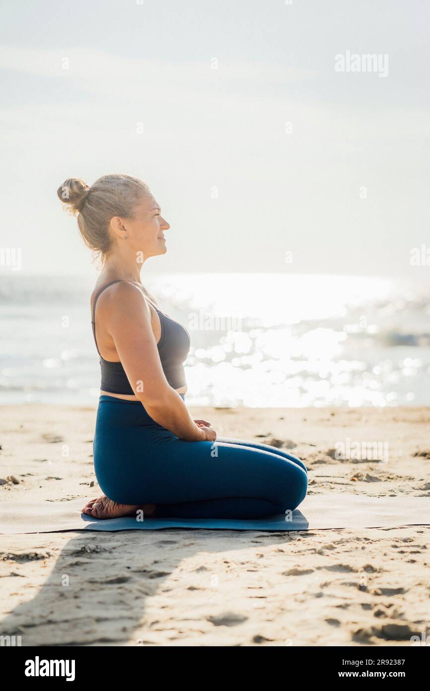 Donna che pratica la respirazione in spiaggia nelle giornate di sole Foto Stock