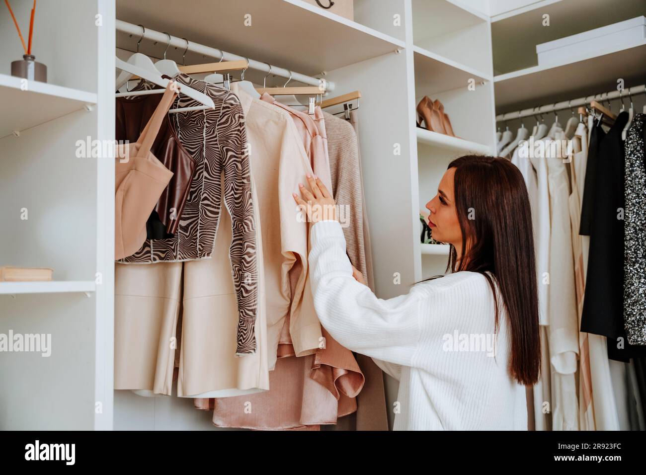 Donna che sceglie i vestiti appesi nell'armadio Foto Stock