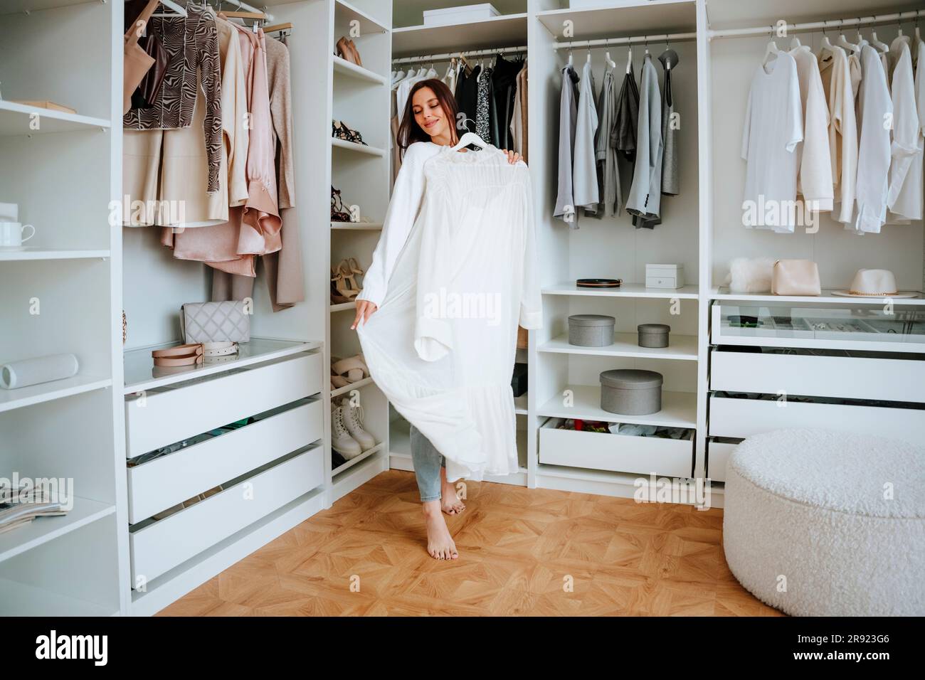 Donna sorridente con vestito bianco in piedi vicino al guardaroba Foto Stock