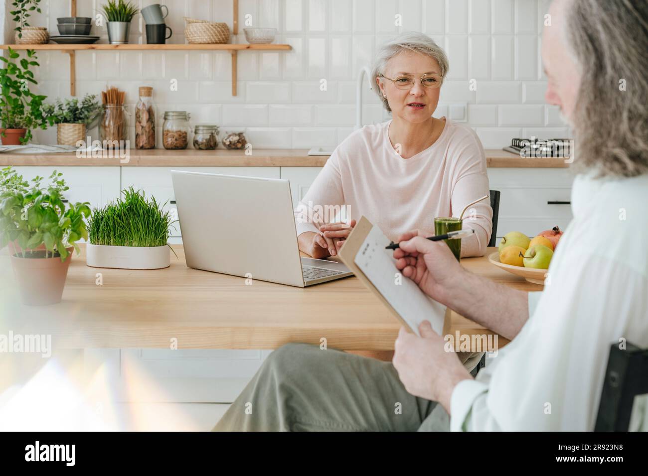 Nutrizionista maturo che discute con il cliente che prepara il menu planner a casa Foto Stock