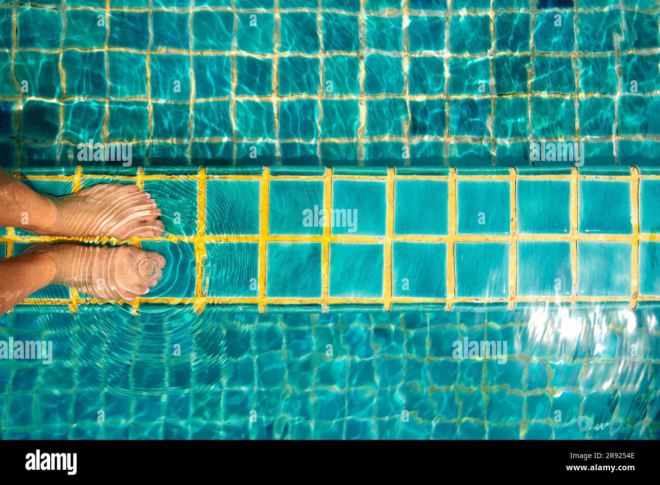 Gambe di donna su pavimento piastrellato in piscina Foto Stock