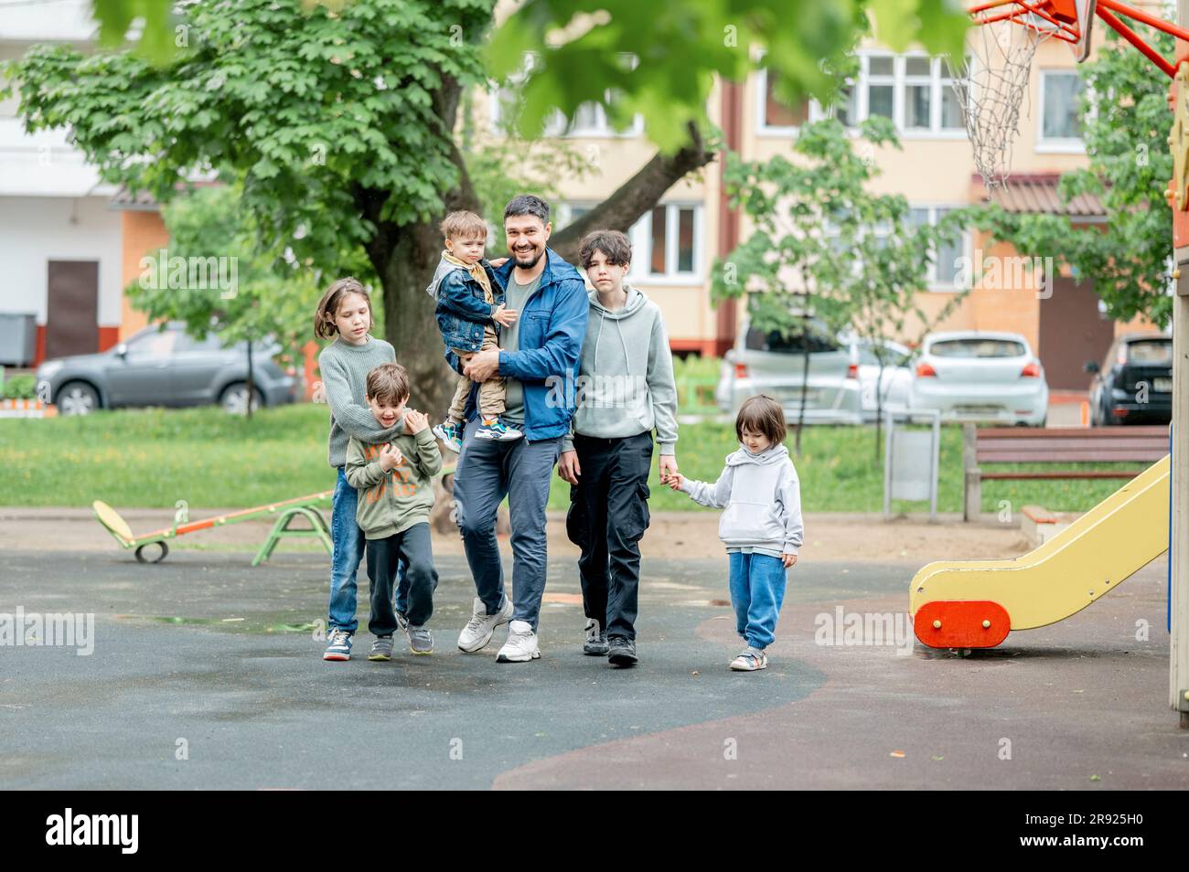 Buon padre che cammina con i bambini nel parco giochi Foto Stock