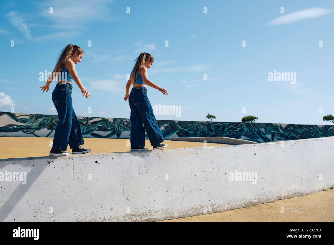 Ragazze che camminano sul muro nel parco per skateboard Foto Stock