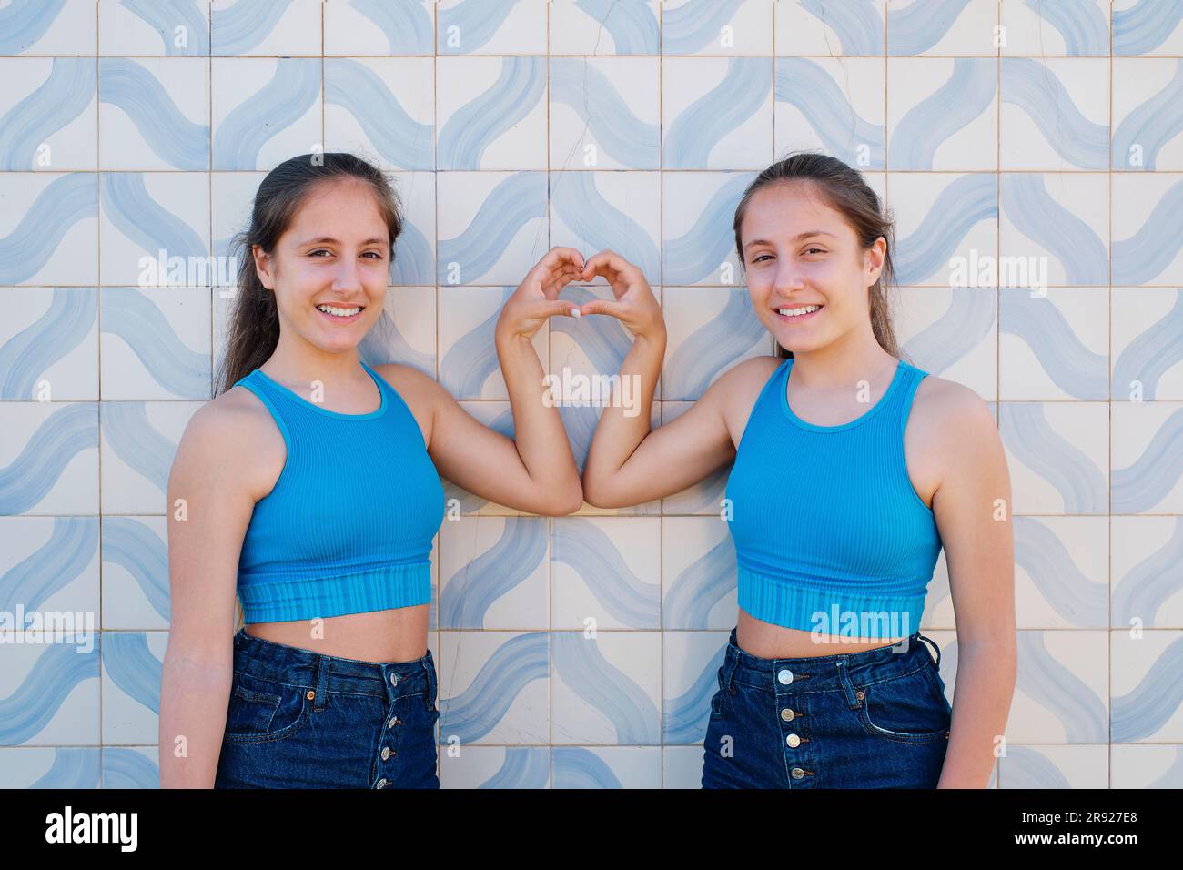 Ragazze felici che gestiscono la forma del cuore davanti al muro Foto Stock