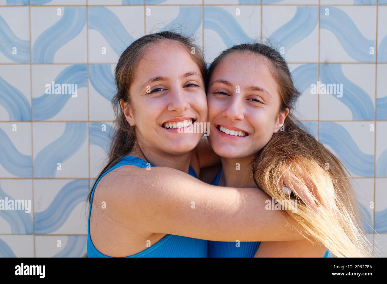 Adorabili sorelle gemelle che si abbracciano davanti al muro Foto Stock