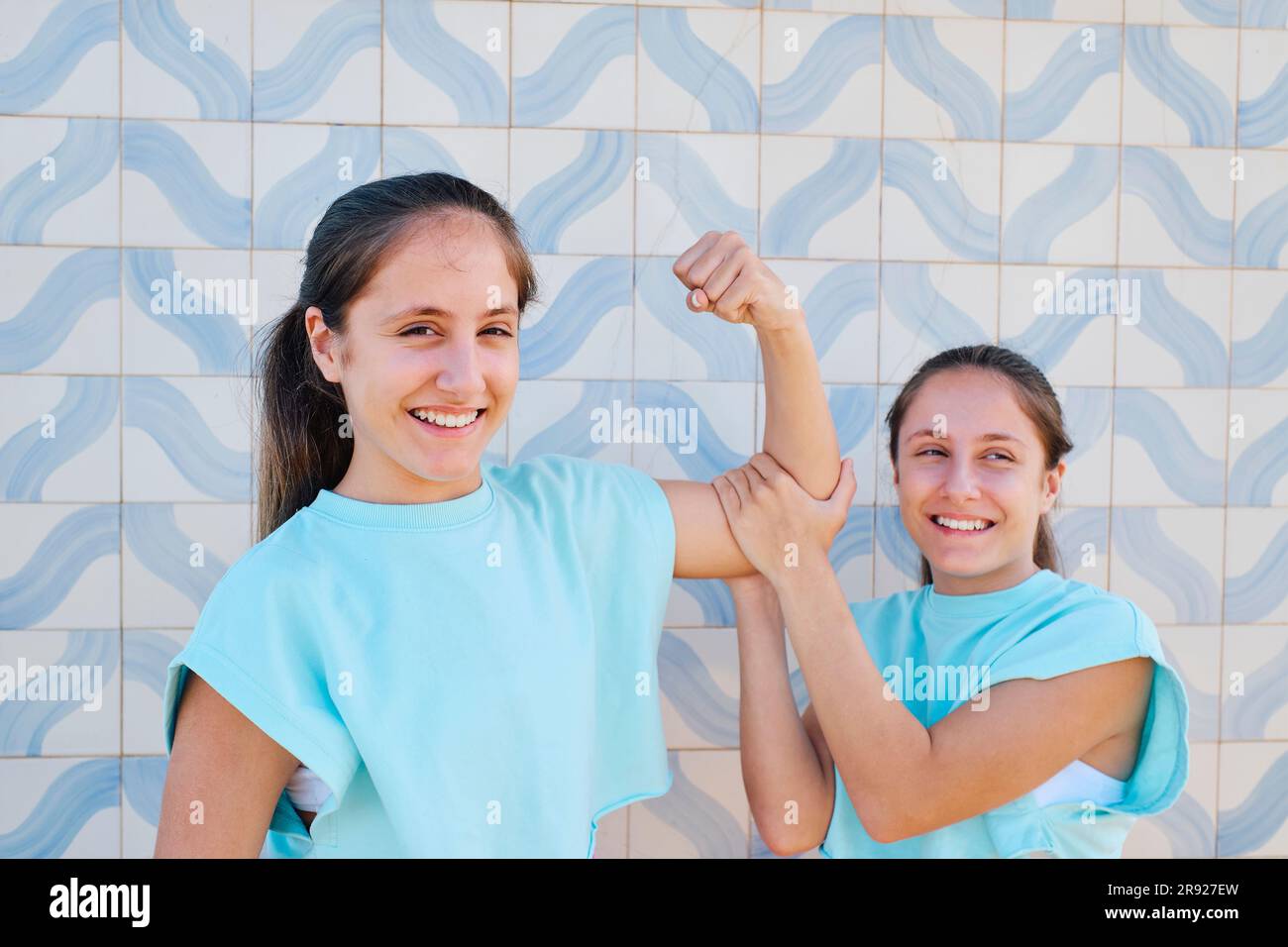 Ragazza felice con muscoli flessionali sorella davanti a un muro modellato Foto Stock