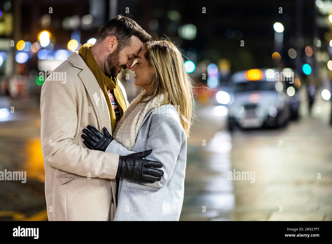 Uomo e donna felici che si abbracciano per strada Foto Stock