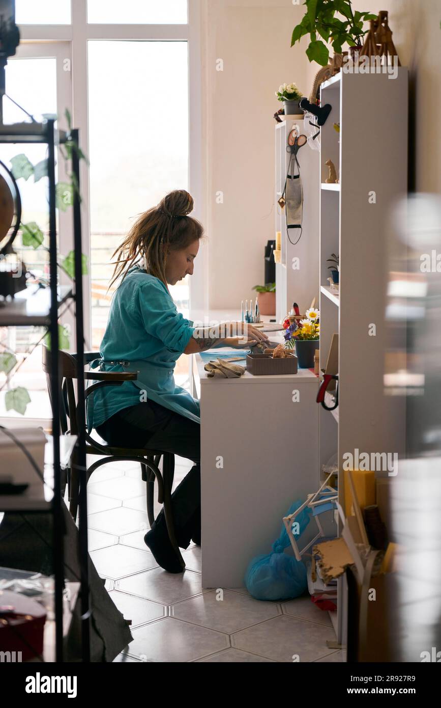 Giovane artigiana che lavora al banco di lavoro a casa Foto Stock