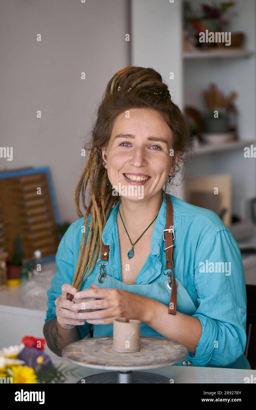 Artigiana sorridente che realizza prodotti artigianali in officina Foto Stock