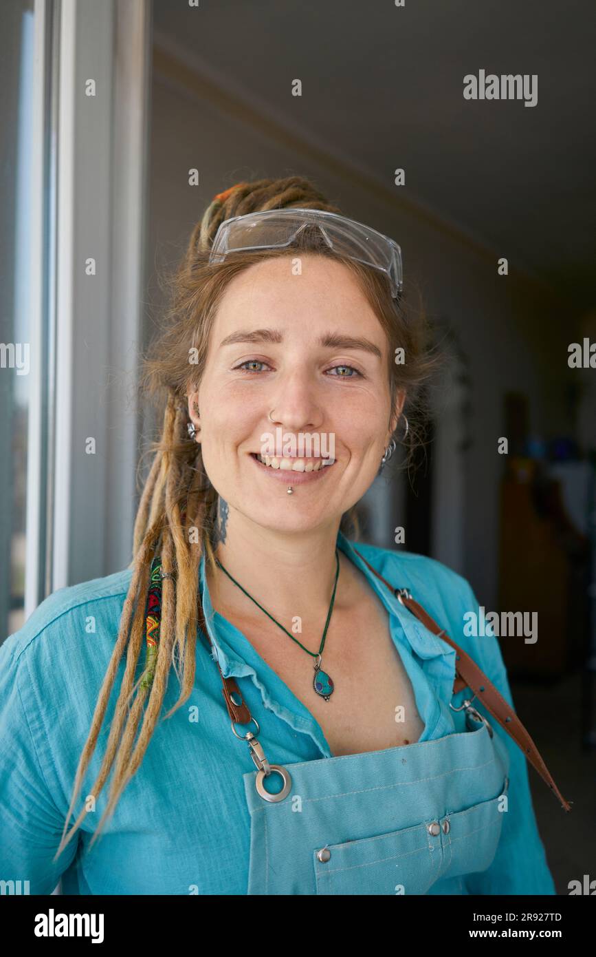 Un'artigiana hipster sorridente in grembiule a casa Foto Stock