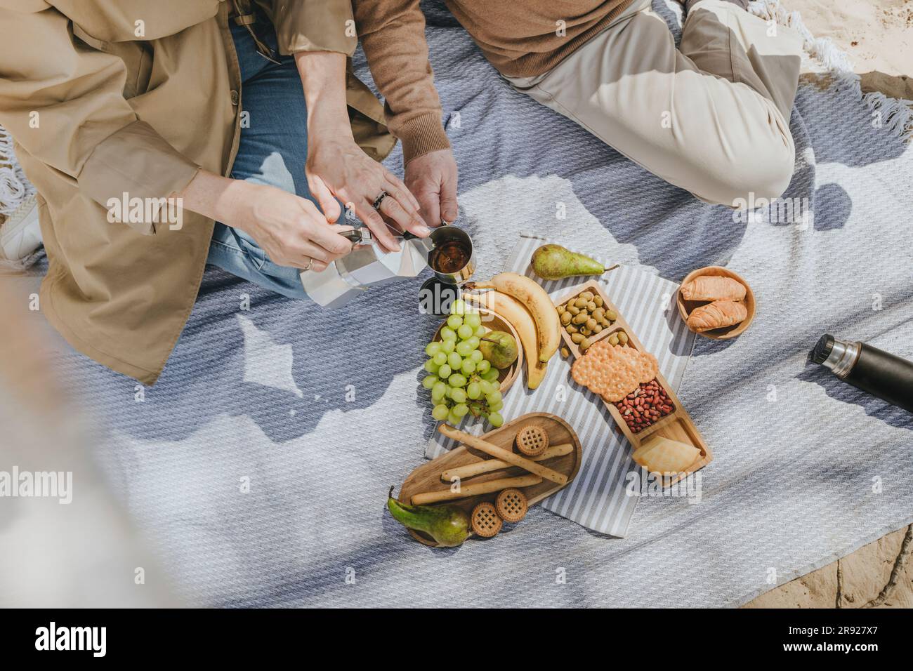 Coppia che si gode un caffè seduto su una coperta da picnic Foto Stock
