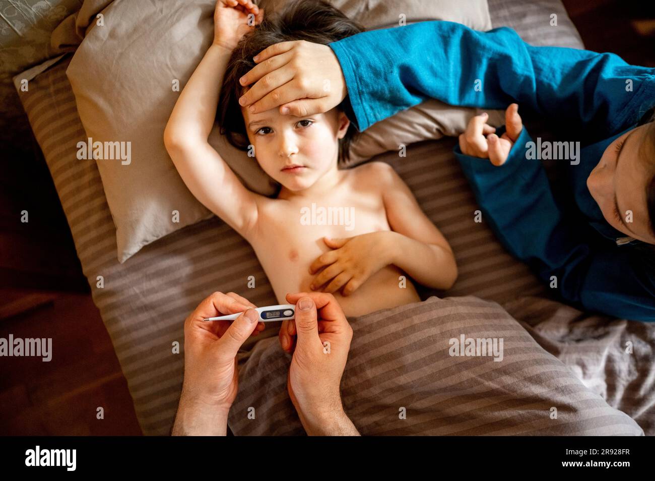 Famiglia che si prende cura di un bambino malato a casa Foto Stock