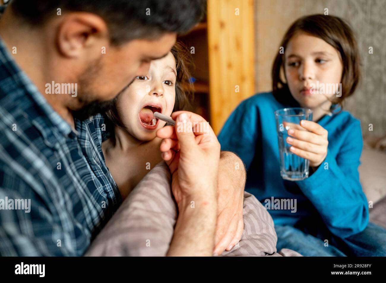 Padre che dà medicine al figlio malato a casa Foto Stock