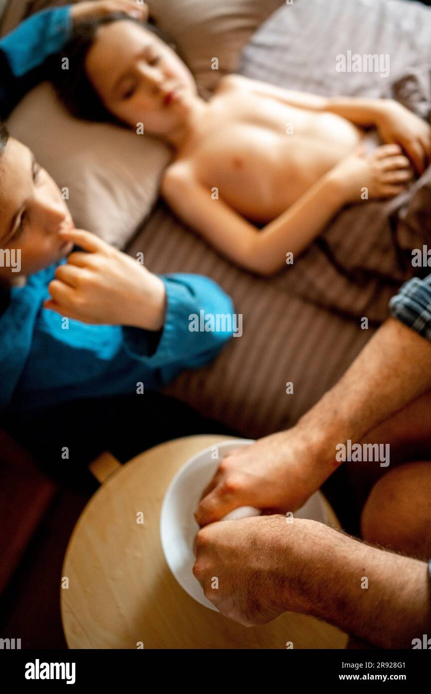 Padre che prepara un asciugamano umido per il bambino malato a casa Foto Stock