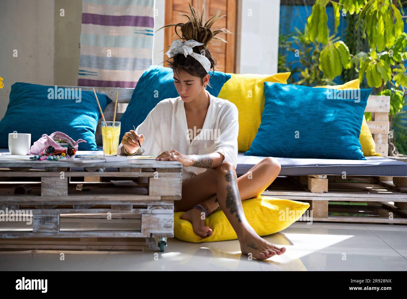 Pittore che dipinge seduto su un cuscino a casa Foto Stock