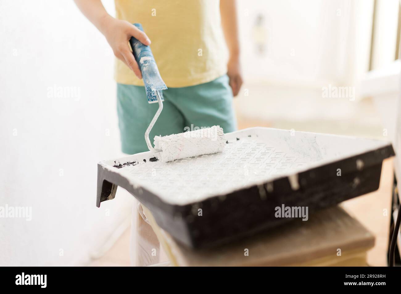 Ragazzo che dipinge con il rullo a casa Foto Stock