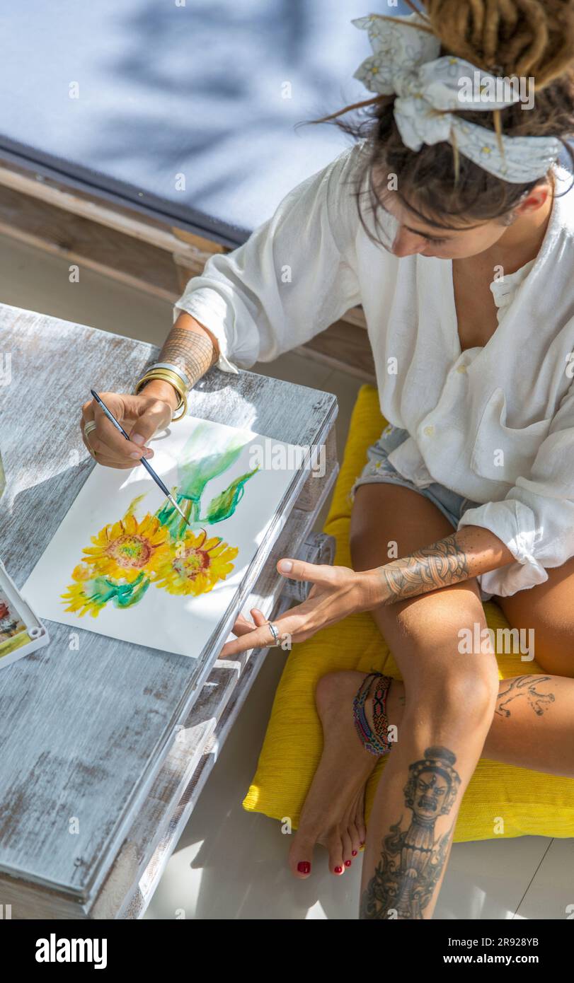 Artista che dipinge girasole su carta a casa Foto Stock