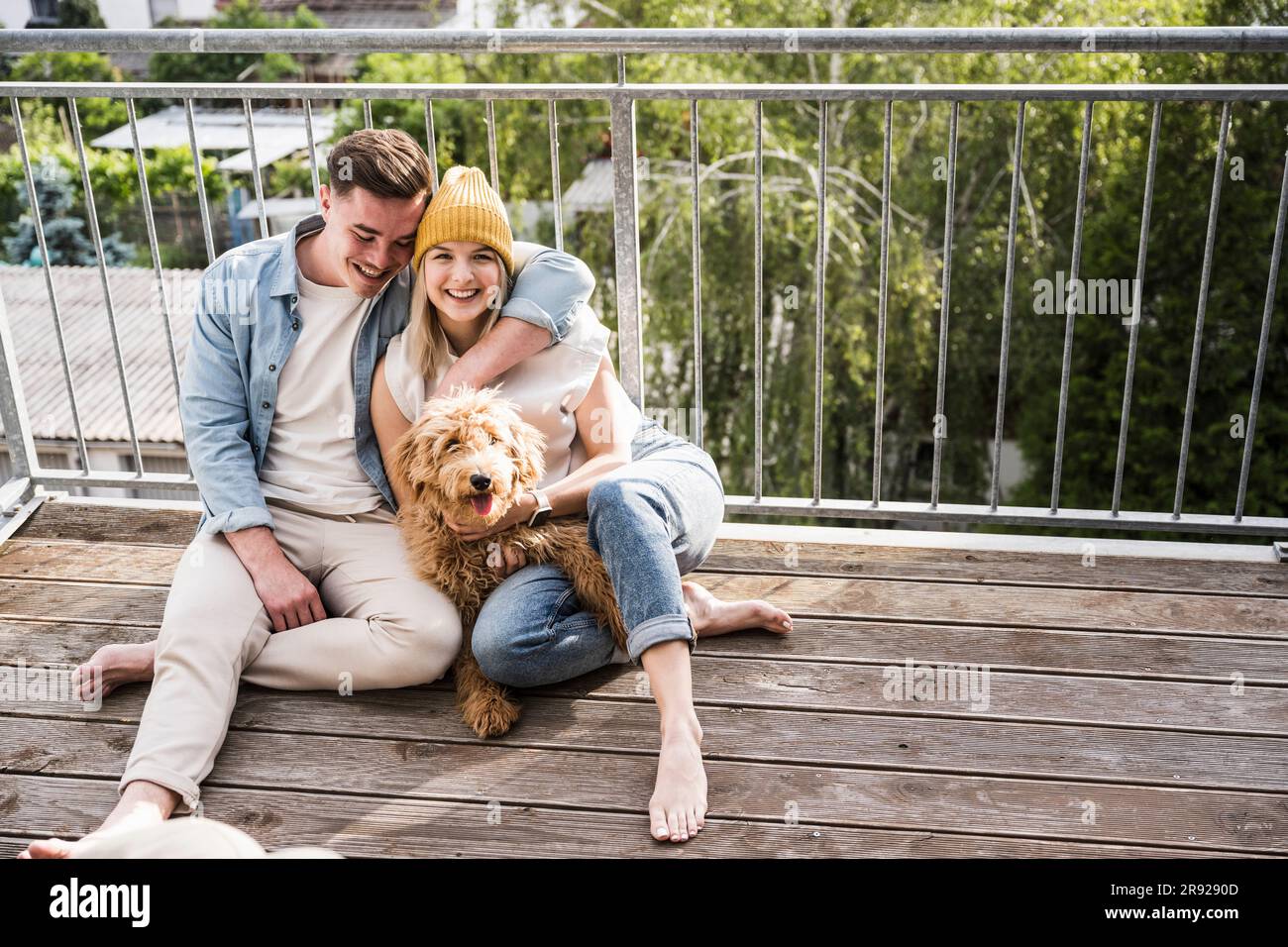 Adorabile giovane coppia seduto con un cane sul balcone Foto Stock