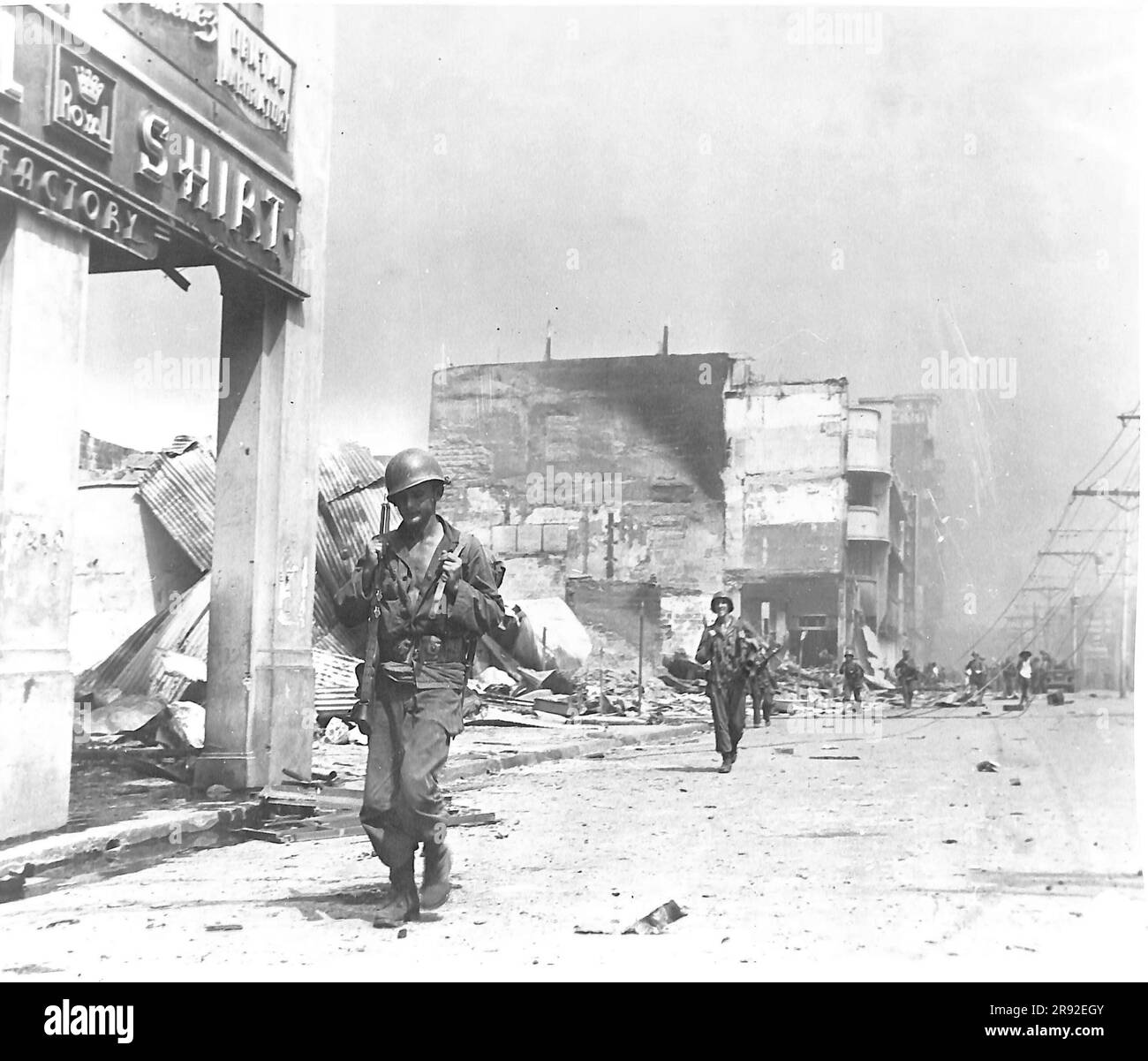 Le truppe americane si spostano attraverso il quartiere commerciale bruciato di Manila, nelle Filippine, sulla strada per il fronte durante la battaglia di Manila del 1945 Foto Stock