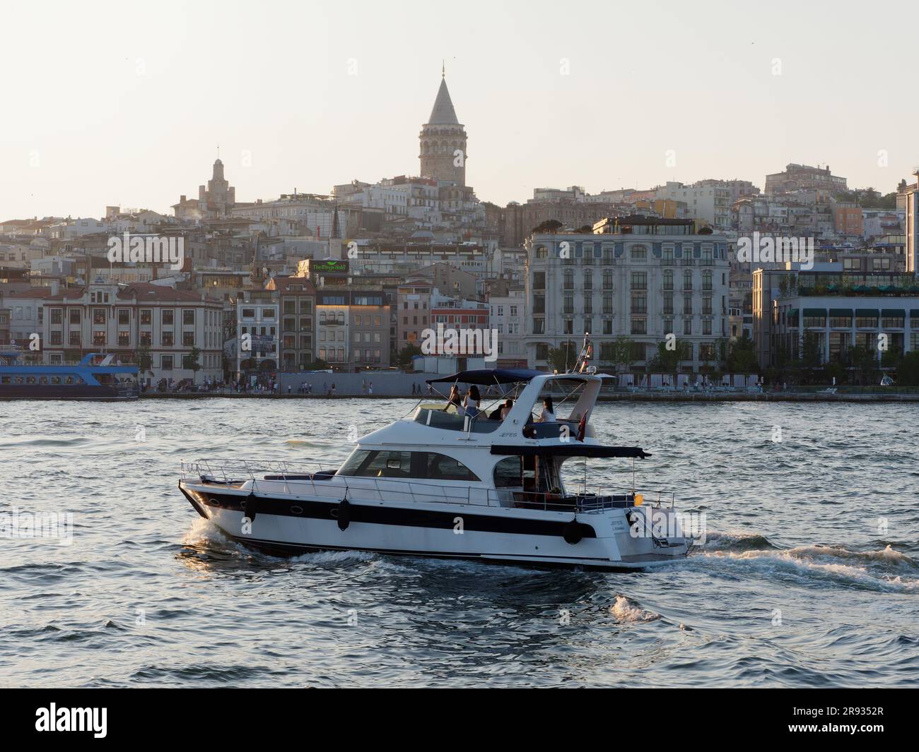 I viaggiatori in vacanza su una barca di lusso sul fiume Corno d'Oro con la Torre Galata alle spalle, Istanbul, Turchia Foto Stock