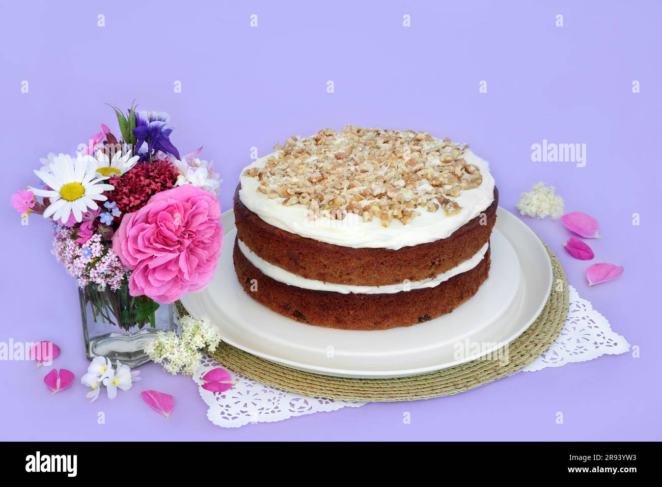 Torta di carote e noci con fiori estivi su sfondo viola. Piatti deliziosi fatti in casa per tè pomeridiano o feste di compleanno. Foto Stock