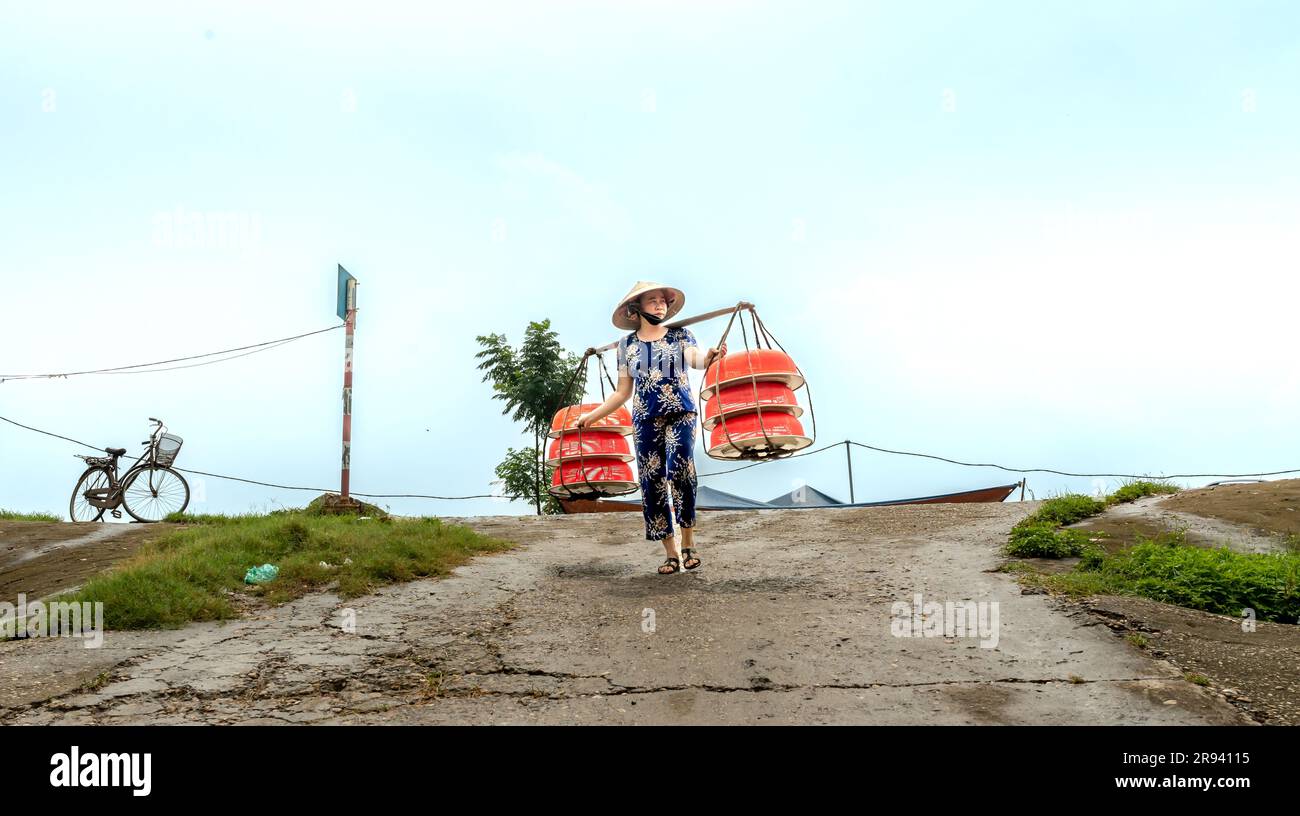 Una donna porta cibo in vendita in un mercato nella provincia di Phu Tho, in Vietnam Foto Stock