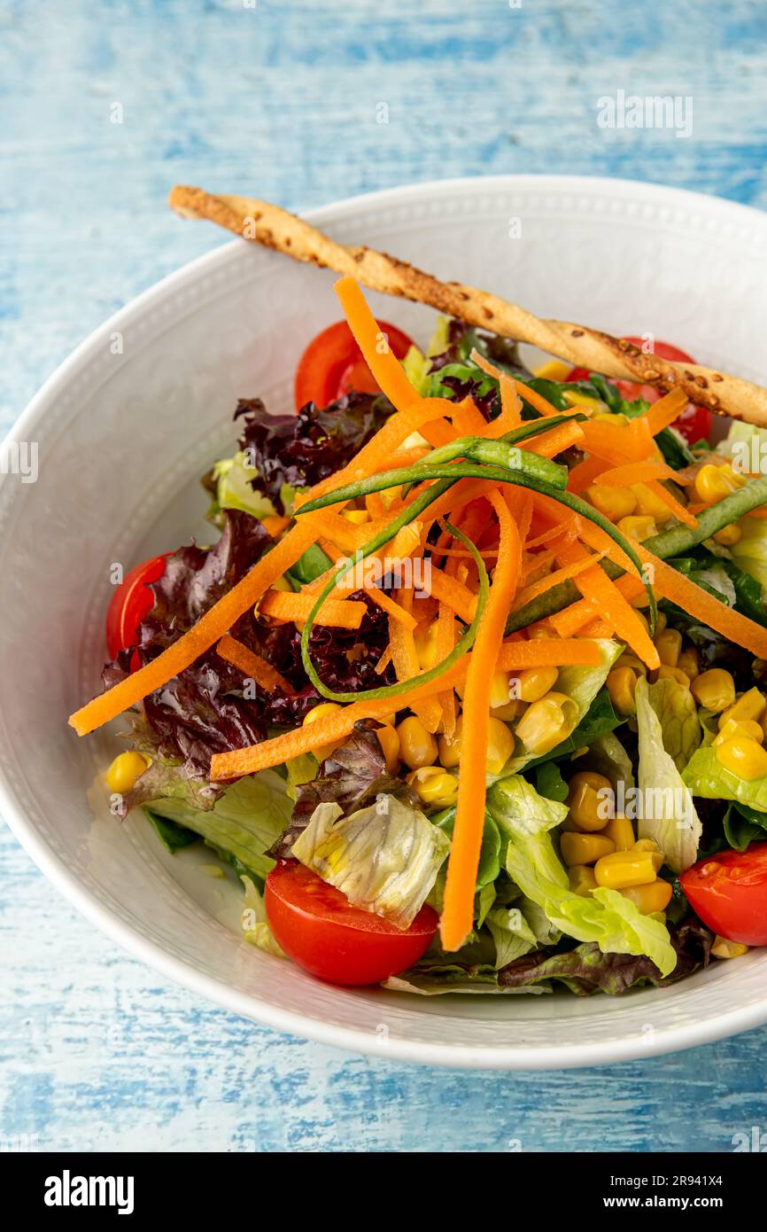 Insalata mista sana in ciotola bianca su tavolo di legno. Insalata mediterranea Foto Stock