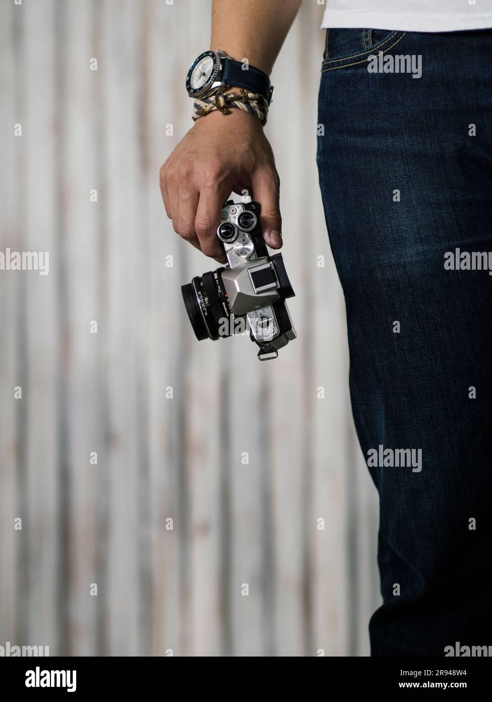Uomo con camicia bianca e jeans blu con fotocamera con mano destra che indossa orologio e bracciale seiko blu e bianco Foto Stock