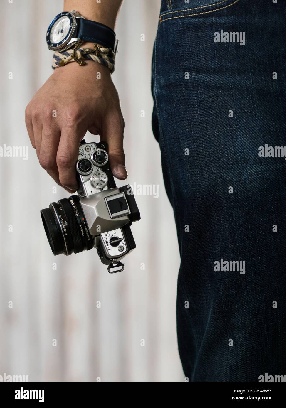 Uomo con camicia bianca e jeans blu con fotocamera con mano destra che indossa orologio e bracciale seiko blu e bianco Foto Stock