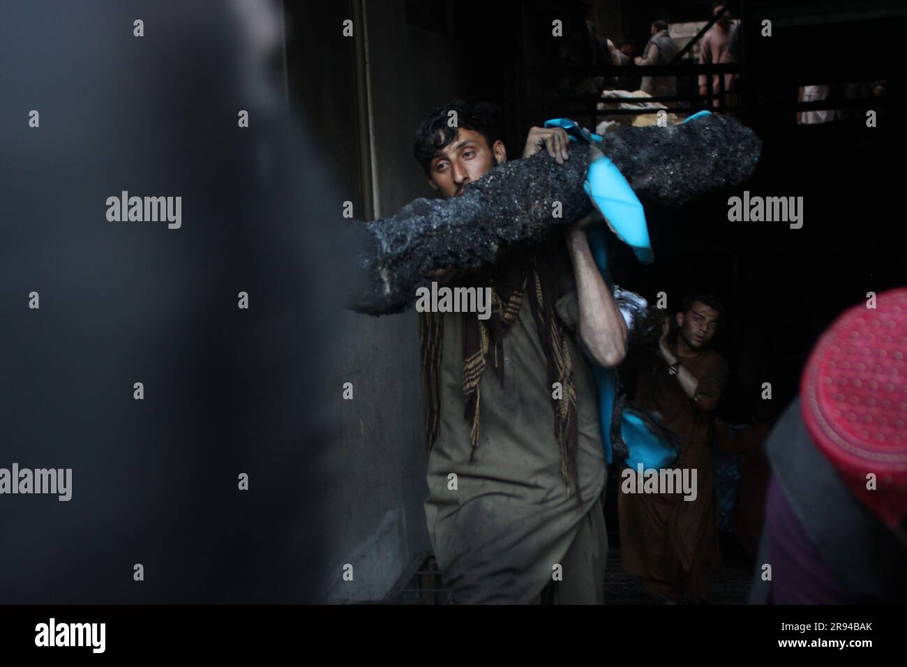 Jalalabad, Afghanistan. 21 giugno 2023. Un uomo afghano porta con sé un rotolo di stoffa mezzo bruciato dal sito di un incendio a Jalalabad, provincia di Nangarhar, Afghanistan, 21 giugno 2023. Proprietà e beni che valgono più di 1 milione di dollari sono stati bruciati in cenere quando un hotel ha preso fuoco nella città di Jalalabad, un funzionario del governo provinciale ha detto giovedì. Crediti: Aimal Zahir/Xinhua/Alamy Live News Foto Stock