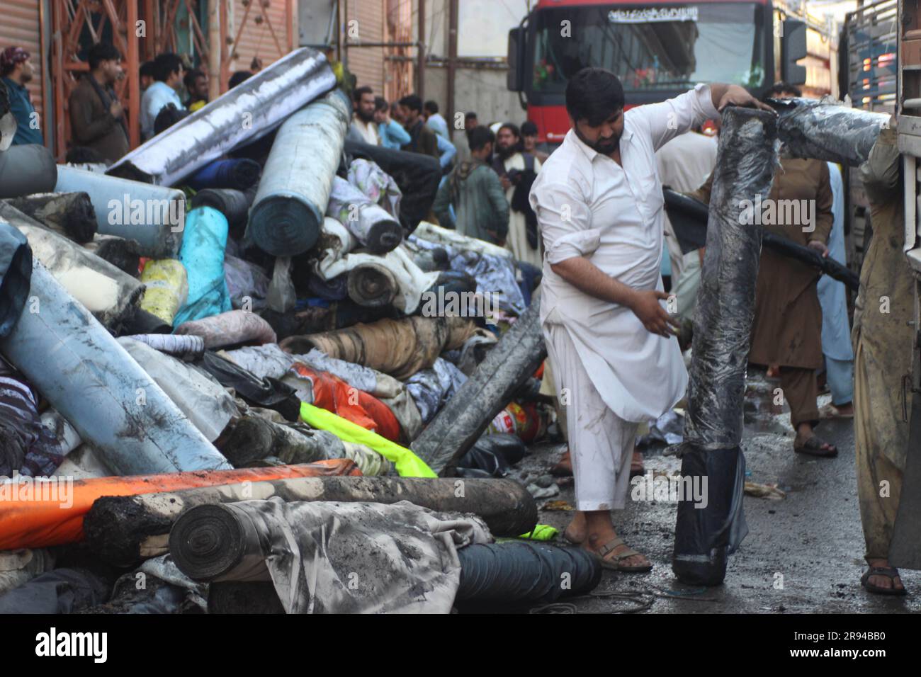 Jalalabad, Afghanistan. 21 giugno 2023. Un uomo afghano porta con sé un rotolo di stoffa mezzo bruciato dal sito di un incendio a Jalalabad, provincia di Nangarhar, Afghanistan, 21 giugno 2023. Proprietà e beni che valgono più di 1 milione di dollari sono stati bruciati in cenere quando un hotel ha preso fuoco nella città di Jalalabad, un funzionario del governo provinciale ha detto giovedì. Crediti: Aimal Zahir/Xinhua/Alamy Live News Foto Stock