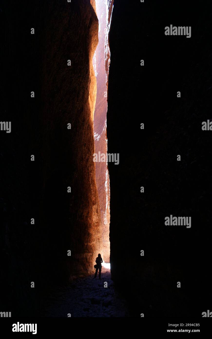 Persona in piedi nel raggio del sole che brilla nella stretta fessura tra le pareti rocciose di Echidna Chasm a Purnululu (Bungles della giungla), Australia Occidentale Foto Stock